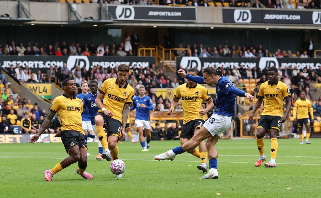 Jack Grealish of Everton shoots whilst under pressure from Jackson Tchatchoua and Santiago Bueno of Wolverhampton Wanderers during the Premier League match between Wolverhampton Wanderers and Everton