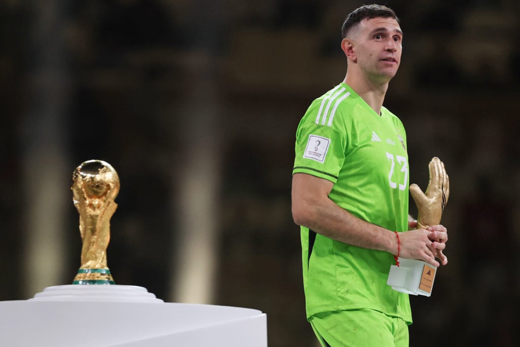 Emiliano Martinez of Argentina walks past the FIFA World Cup Qatar 2022 Winner's Trophy after presented the adidas Golden Glove trophy at the award ceremony following the FIFA World Cup Qatar 2022 Final match between Argentina and France