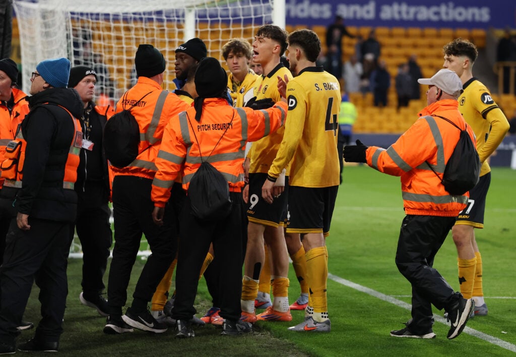 Members of Pitch security stand in front of Jorgen Strand Larsen of Wolverhampton Wanderers as he clashes with fans of Wolve
