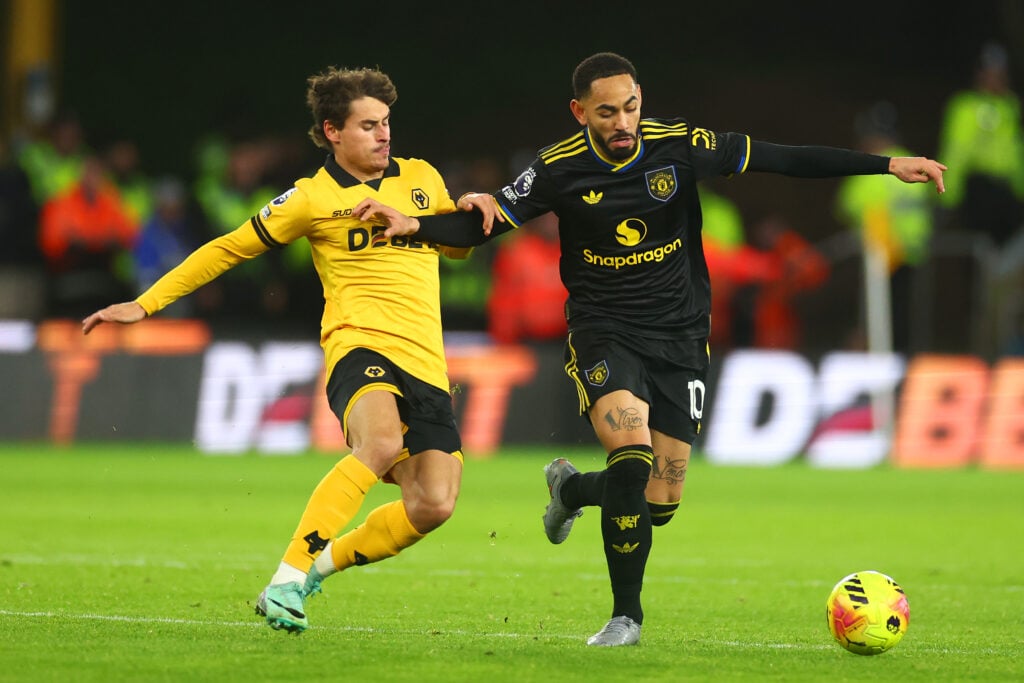 Matheus Cunha running with the ball as Hugo Bueno tries to tackle him