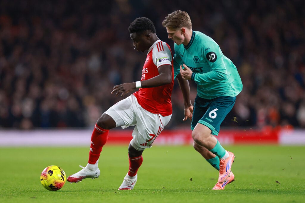 David Moller Wolfe battles Bukayo Saka for the ball.