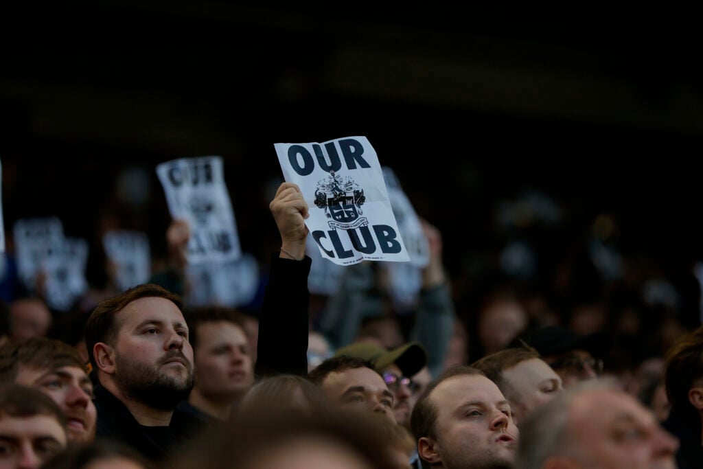 A Wolves fan holds up a sign protesting the owners.
