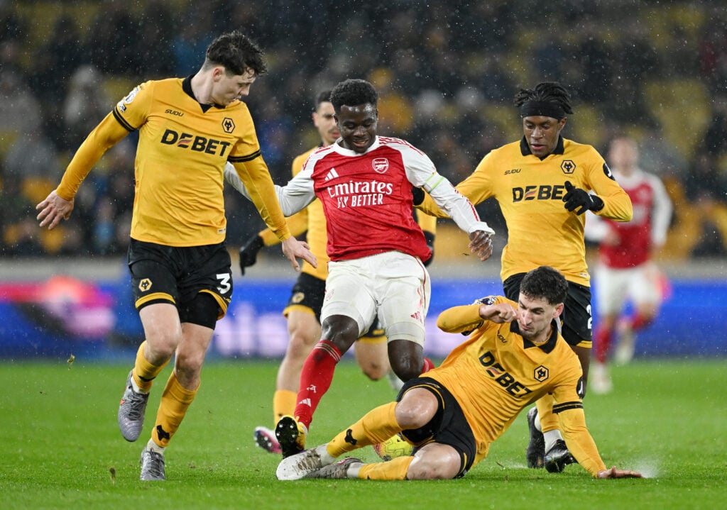 Santiago Bueno and Wolves players challenge Bukayo Saka.